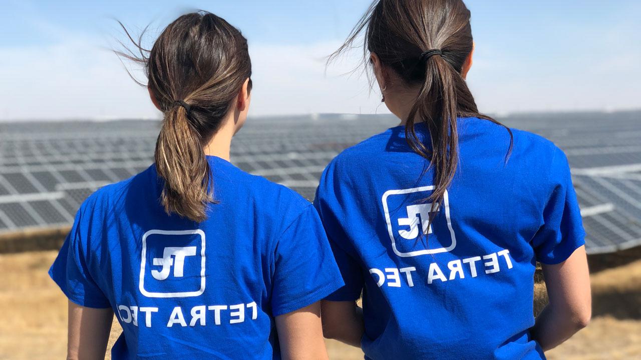 哈萨克斯坦，两名身穿蓝色利乐全球最大体育平台衬衫的女子背对着镜头，俯瞰着一座太阳能发电厂